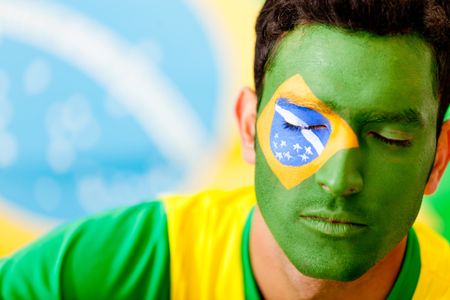 Man portrait with flag from Brazil painted on his face