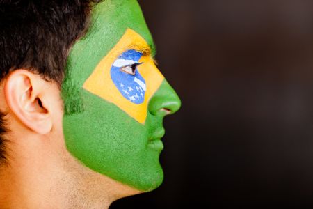 Profile view of a Brazilian man with flag painted on his face