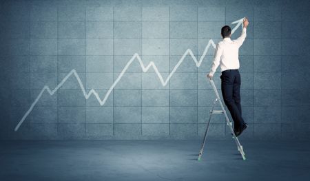 A man standing on a ladder and drawing a chart on blue wall background with exponential progressing curve, line