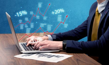 An elegant businessman working on graph statistics calculation using a laptop with clear blue background concept