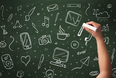 A person drawing media and communication icons on school blackboard with chalk