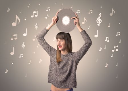 Young lady holding vinyl record on a brown background with musical notes behind her