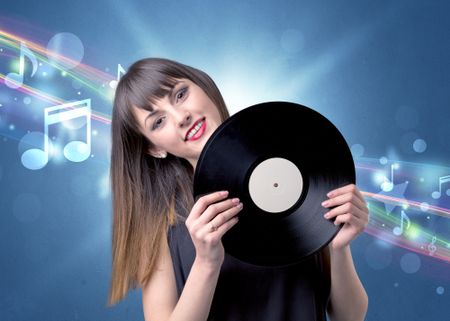 Young lady holding vinyl record on a blue background with musical notes behind her