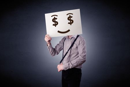 Young casual businessman hiding behind a greedy face drawing on cardboard