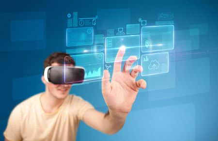 Young impressed man wearing virtual reality goggles with blue squares containing data at his fingers 