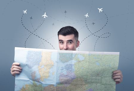 Handsome young man holding a map with little planes and their paths above him