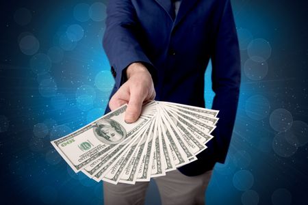 Young businessman holding large amount of bills with shiny blue background