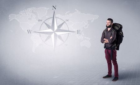 handsome-young-man-standing-backpack-back-1007462458 Handsome young man standing with a backpack on his back and a compass and a world map in the background