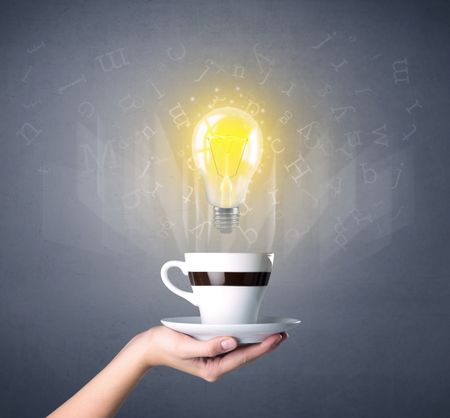 Young female hand holding coffee cup with a lightbulb and alphabet letters above it 