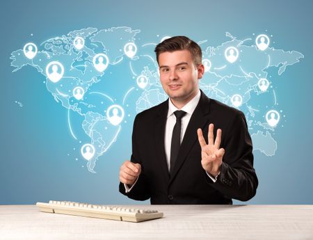 Young handsome businessman sitting at a desk with a blue world map behind him