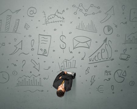 Young contemplating businessman stands in front of business graphics