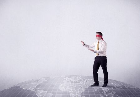 Young blindfolded businessman steps on a grey world map