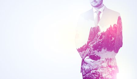 Young businessman in suit standing with sunny snowy mountain and trees graphic.