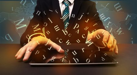 Young man in suit and formal clothing typing with letters around