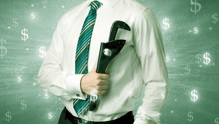 Handsome businessman holding tool with dollar symbols around and with green background