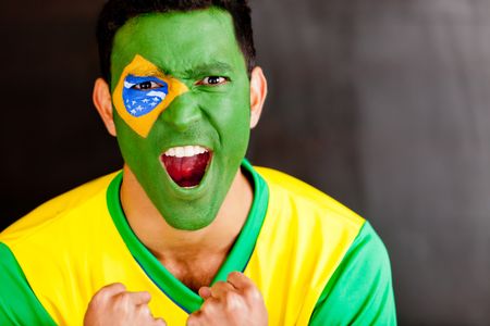 Brazilian man shouting with the flag painted on his face