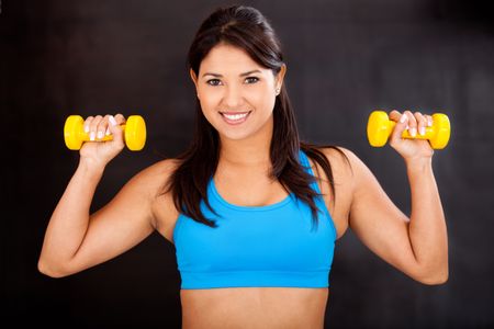 Beautiful athletic woman lifting free-weights and smiling