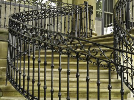 Ornate handrail of wrought iron along curved staircase to main entrance of public museum