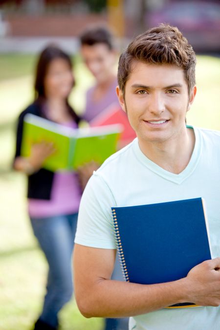 male-student-carrying-notebooks-outdoors-smiling-102129289 Male student carrying notebooks outdoors and smiling