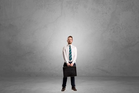 Alone handsome businessman standing in a dark empty room