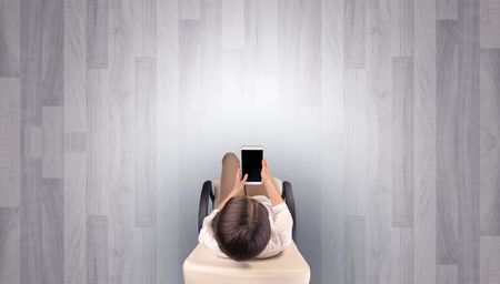 Empty office with woman in a chair and device on her hand
