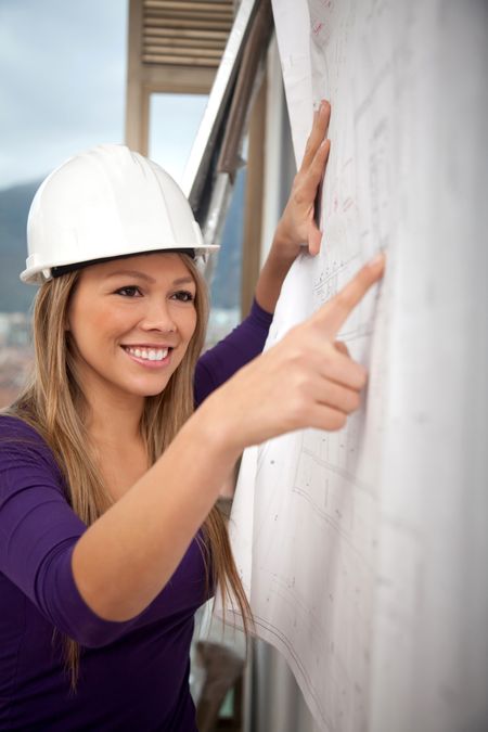 Female engineer at a construction site looking at blueprints
