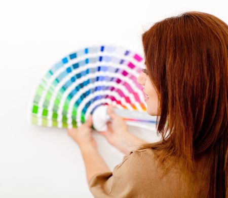 Woman choosing color to paint the wall from a guide