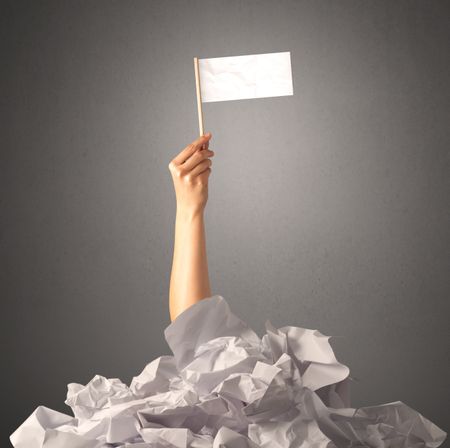 Female hand emerging from crumpled paper pile holding a white blank flag