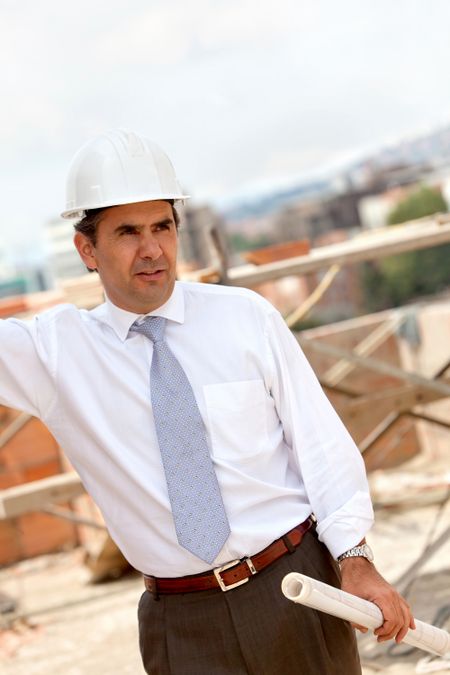 male engineer at a construction site holding blueprints