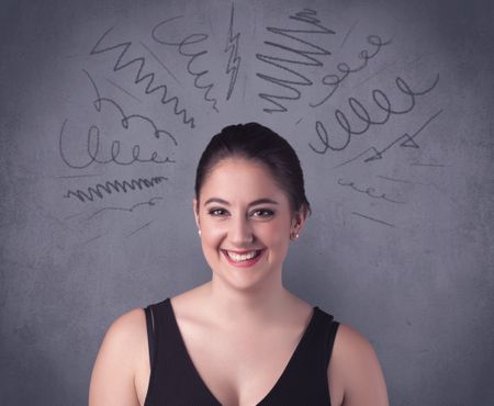 A cute female student making funny face expressions with pressure and problems in her head illustrated by drawn lines, marks and spirals on the urban wall background concept.