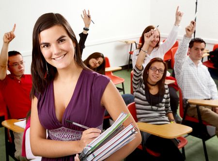college student smiling with notebooks in a classroom
