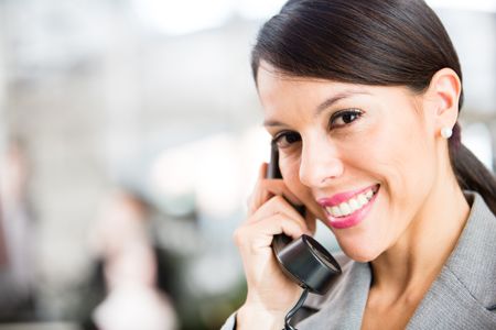 Business woman on the phone taking a call and smiling