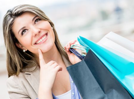 Pensive shopping woman holding bags and smiling