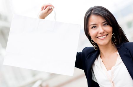 Female shopper holding a shopping bag and smiling