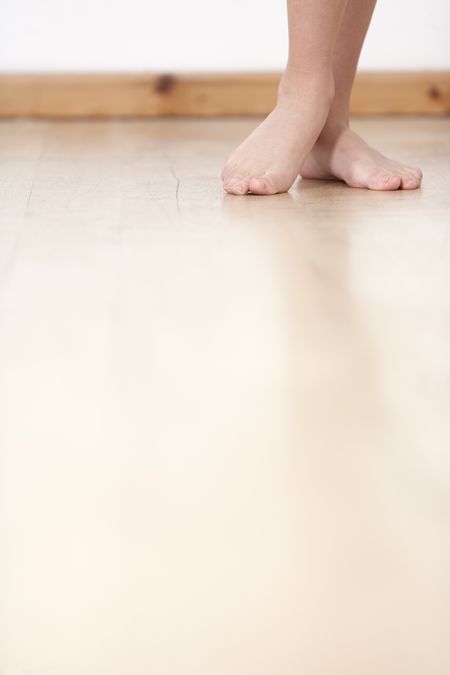 Woman's legs on wooden floor against a white wall back drop.