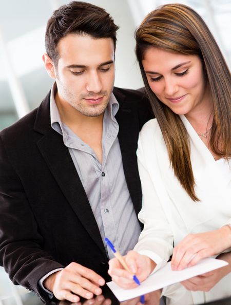 Successful business couple signing a document and smiling