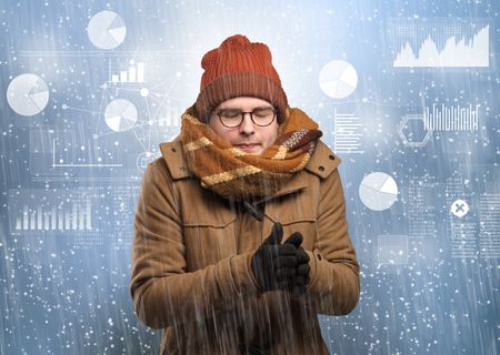 Young businessman shivering with graphs, reports and chart concept
