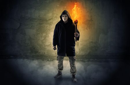 Wayfarer with burning torch in his hand in front of a crumbly wall concept
