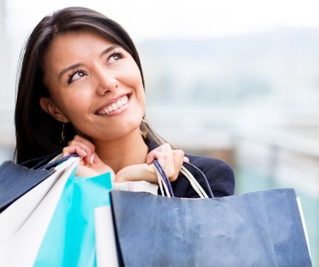 Pensive shopping woman holding bags and looking up