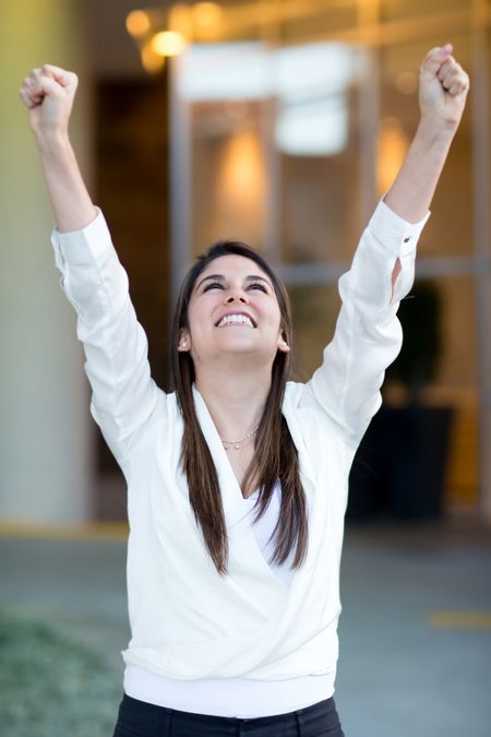 Successful businesswoman celebrating her triumph with arms up