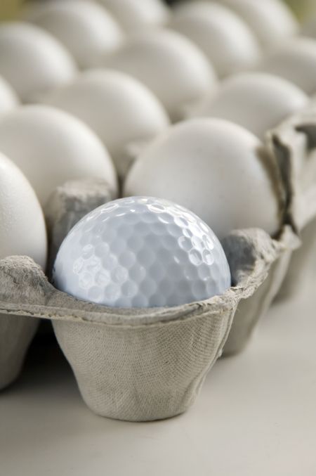 Golf ball and eggs in an egg carton