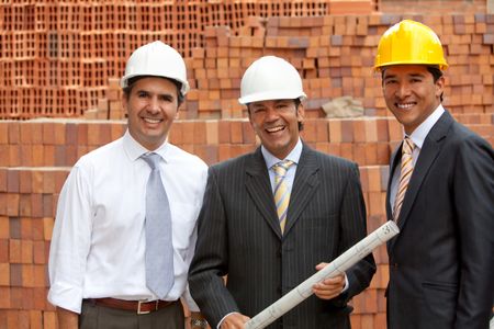 Architects at a construction site holding the blueprints