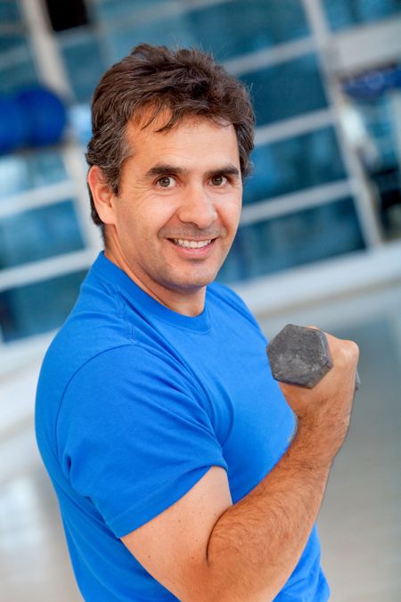Man at the gym lifting a free-weight and smiling