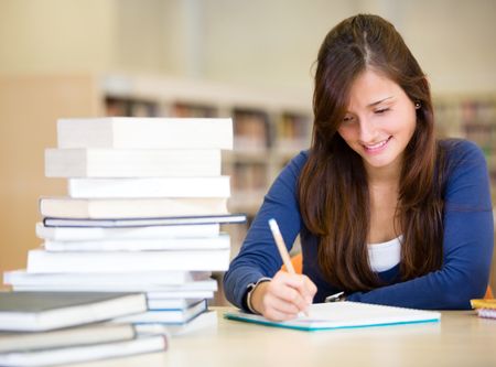 Student at the library with a pile of books