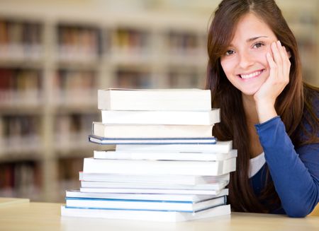 Female librarian with a pile of books and smiling
