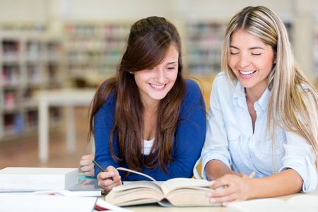 Young female students at the library reading a book