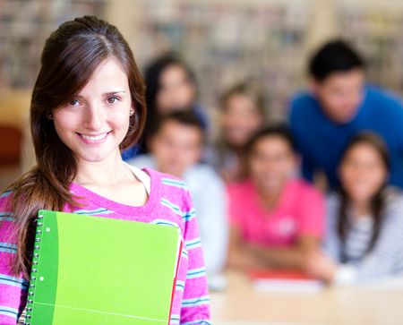 Woman holding notebooks with a group of students at the background