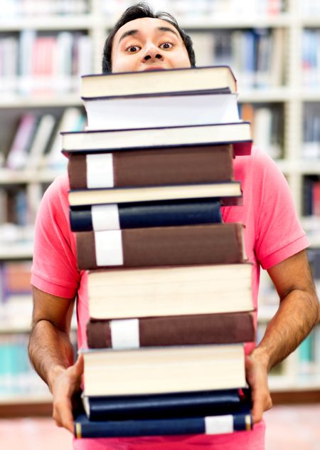 Man carrying a pile of heavy books at the library