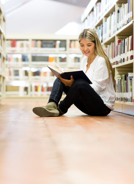 Female student at the library reading a book