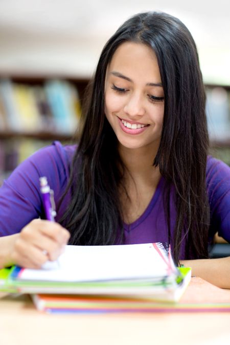 Happy female student taking notes and smiling